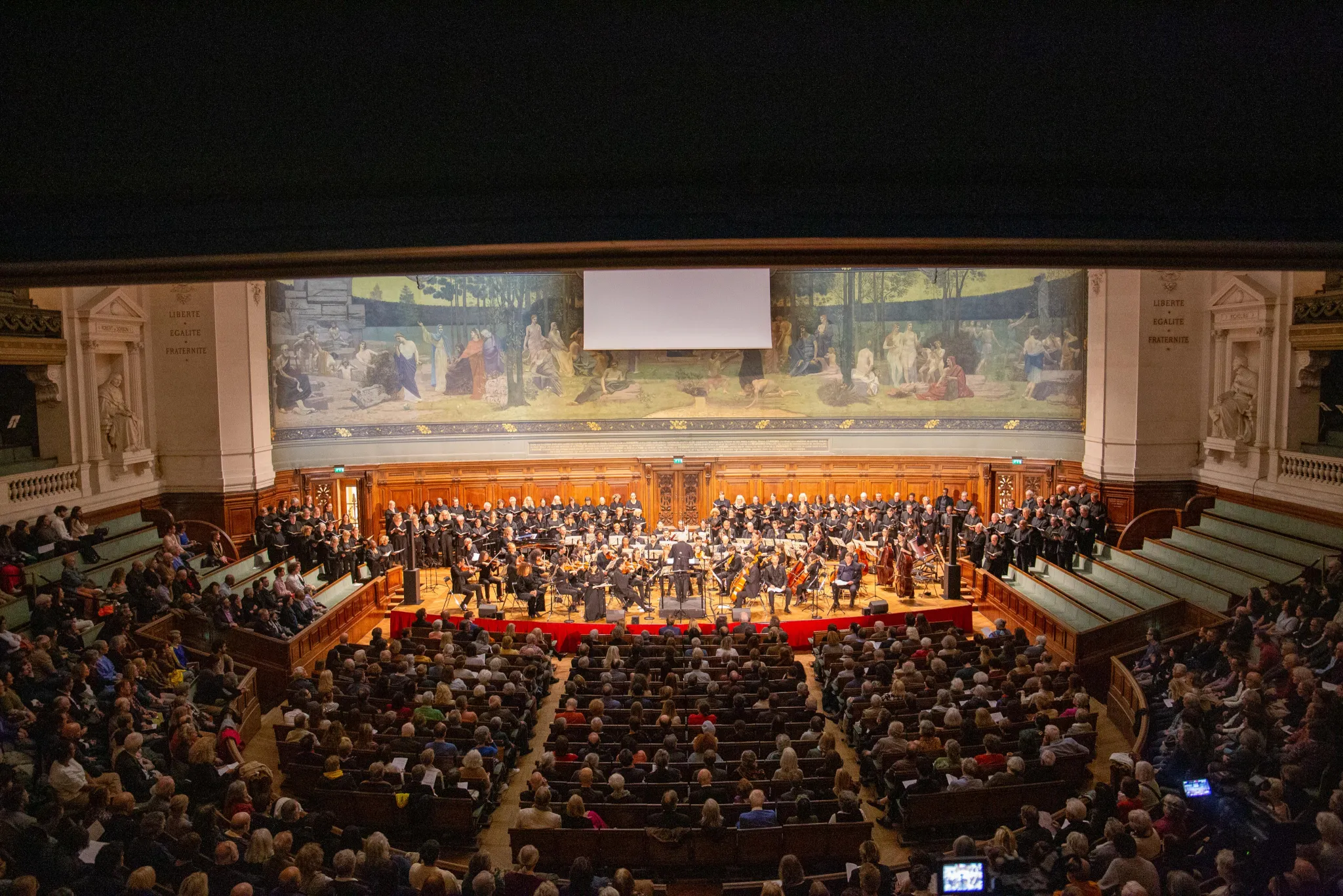 Vue d'ensemble du Grand Amphithéâtre de la Sorbonne comble lors du concert Defiant Requiem : Verdi à Terezín, avec le chœur, l'orchestre et le public, 19 mai 2026