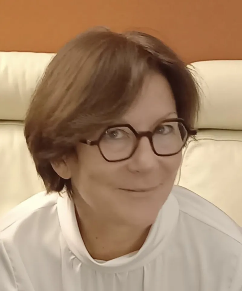 Femme châtain souriante avec lunettes devant canapé écru
